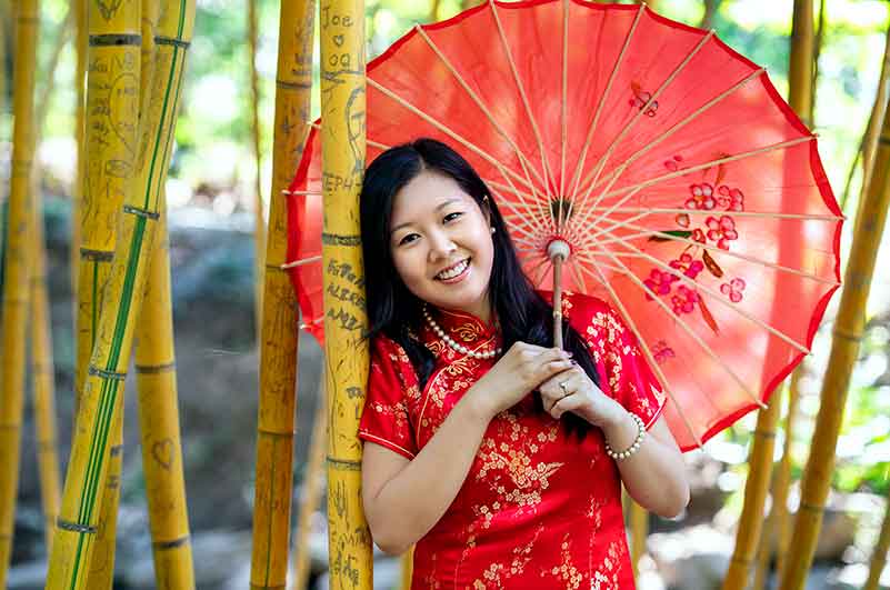 Wearing tradition chinese red with red umbrella stand by bamboo